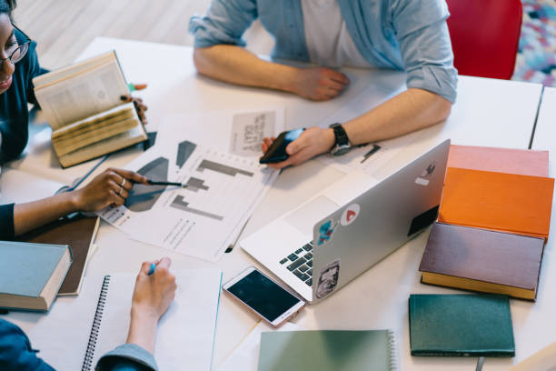 istock Multiracial students looking at diagrams on documents and checking information in books 1459734689