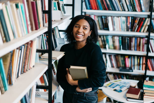 istock Excited black woman choosing book in library 1459734753