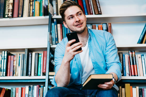 istock Casual male browsing phone spending time in library 1459734821