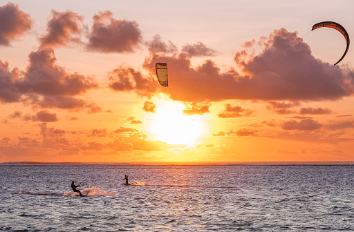 A surfer doing an amazing jump and splashing water in front of the sunset at the sea