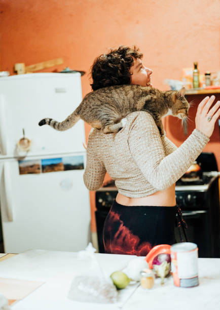 istock Happy young generation z non-binary person dances in a kitchen with a cat 1459736048