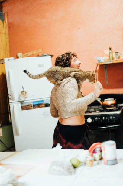istock Happy young generation z non-binary person dances in a kitchen with a cat 1459737318