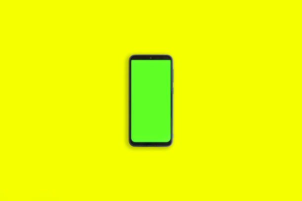 istock Phone with vertical green screen with chroma key isolated yellow background. Mock Up Display. Smartphone gadget for advertising. Top above view. Mobile phone with empty blank screen. Layout template 1459742220