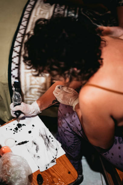 istock Non binary tattoo artist giving a at-home tattoo in a hostel 1459742241
