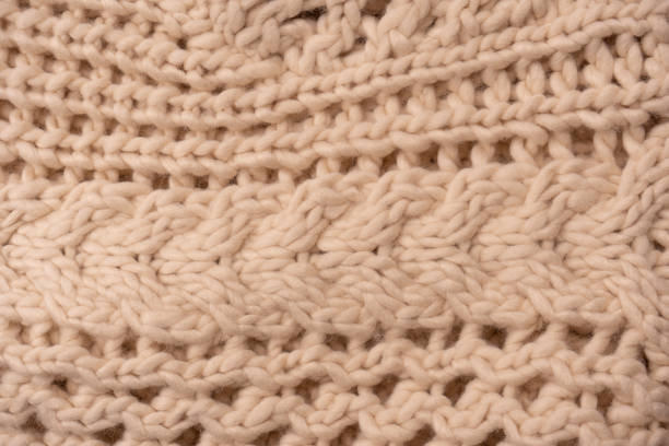 istock A fragment of beige knitted fabric, knitted from white sheep wool. 1459752155