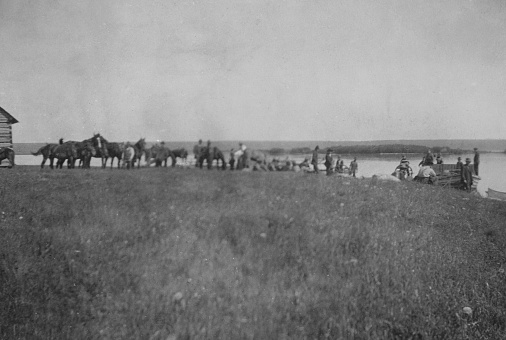 Expedition group loading equipment and horse to cross Buffalo Bay at Lesser Slave Lake in Alberta, Canada. Vintage photograph ca. 1914.