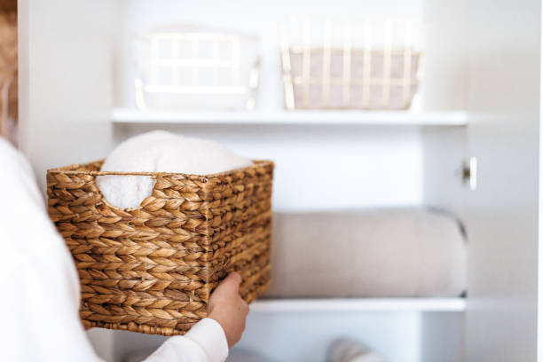 istock Woman organizing clothes on shelves in white opened wardrobe, folding laundry in baskets. Space organization and storage system. 1459754794