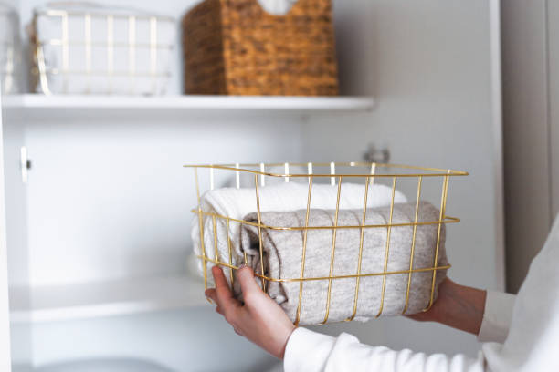 istock Woman organizing clothes on shelves in white wardrobe, folding laundry in baskets. Space organization and storage system 1459754875