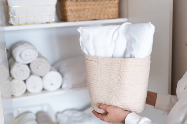 istock Woman organizing clothes on shelves in white opened wardrobe, folding laundry in baskets. Space organization and storage system. 1459754910