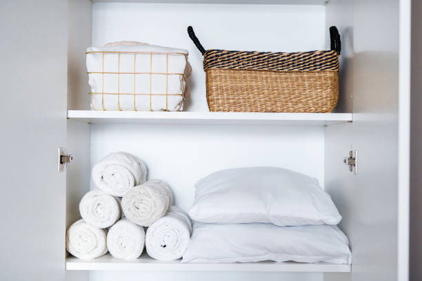 istock White laundry, pillows, towels organized and folded in baskets on shelves in white wardrobe. Space organization 1459754963