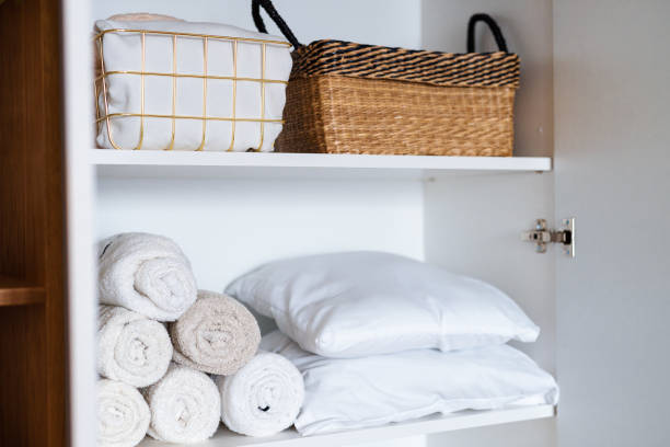 istock White laundry, pillows, towels organized and folded in baskets on shelves in white wardrobe. Space organization 1459754968