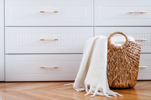 Wardrobe drawers and woven wicker basket for laundry with white blanket, close up.