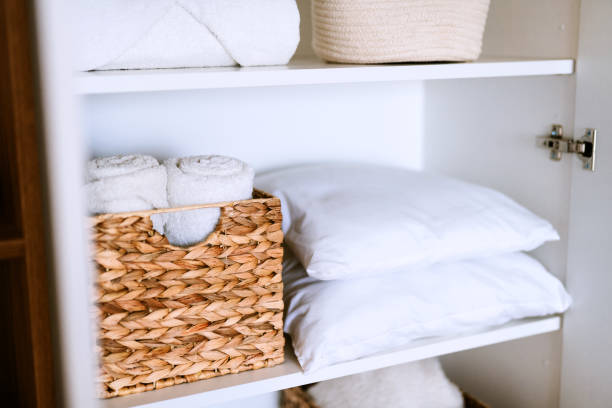 istock White laundry, pillows, towels organized and folded in baskets on shelves in white opened wardrobe. Space organization and storage system. 1459755222