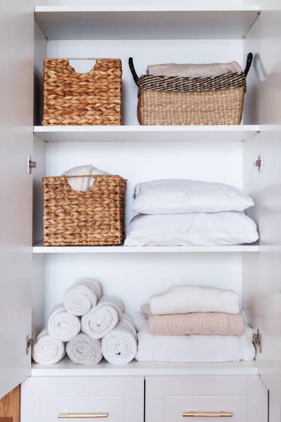 istock Clothes, pillows, towels organized and folded in wicker baskets on shelves in white wardrobe 1459755936
