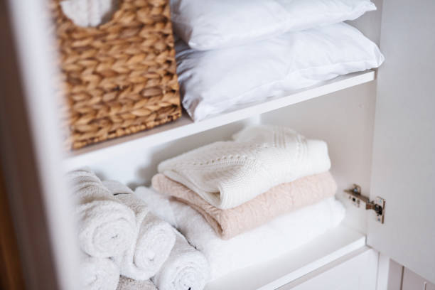 istock White laundry, pillows, towels organized and folded in baskets on shelves in white wardrobe. Clothes organization and storage system 1459755939
