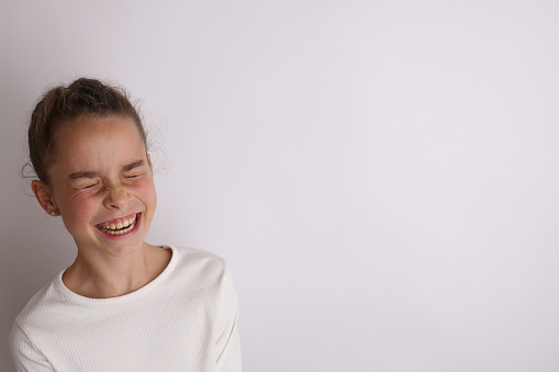 Little emotional teen girl in white shirt 11, 12 years old on an isolated white background. Children's studio portrait. Place text, to copy space for inscription, advertising children's goods.