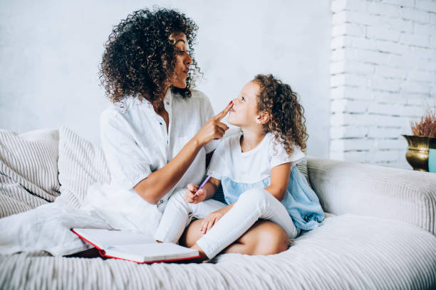 istock Mother playing with charming daughter sitting on sofa 1459762255