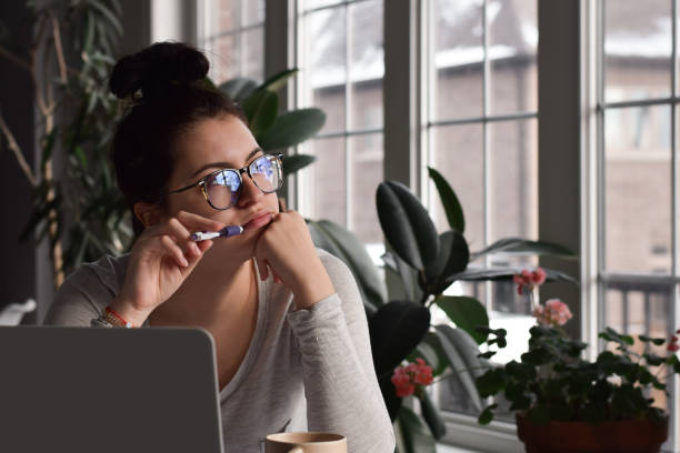 istock Young girl student in glasses sitting at desk in deep thought 1459763336