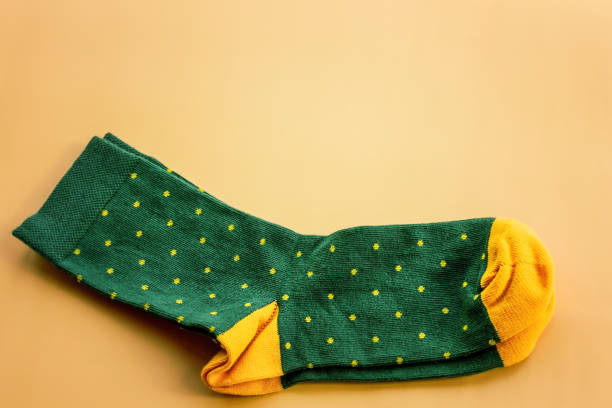 Green socks with yellow polka dots. A pair of socks on a beige background. stock photo