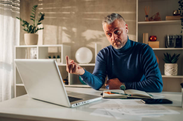 istock Middle aged man showing middle finger to a laptop screen while working at home 1459767432