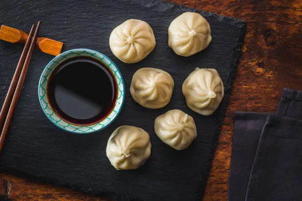 Photo of Xiaolongbao, traditional steamed dumplings. Xiao Long Bao buns on cutting board.