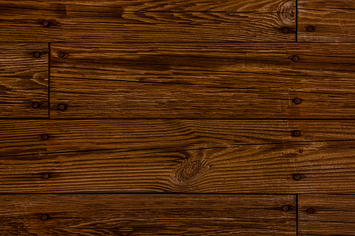 Detail of an old wooden floor. Wood knots, cracks, stains, scratches and other damages are strongly expressed. All planks have a strong clear texture of wood. A wood grain pattern featuring even grains of wood running horizontally across the image. Compounds of the planks are clearly visible.