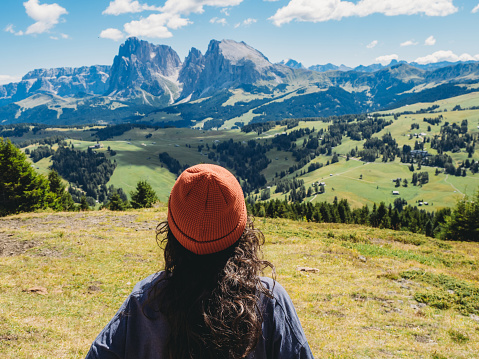 A woman is admiring the view of Seiser Alm mountain in Italy. She's looking at view.