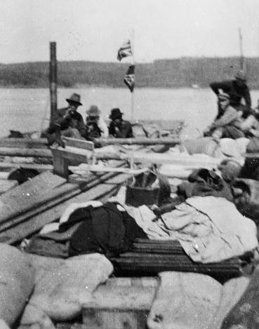 Group of men and equipment aboard a scow boat on the Athabasca River in Alberta, Canada. Vintage photograph ca. 1915.