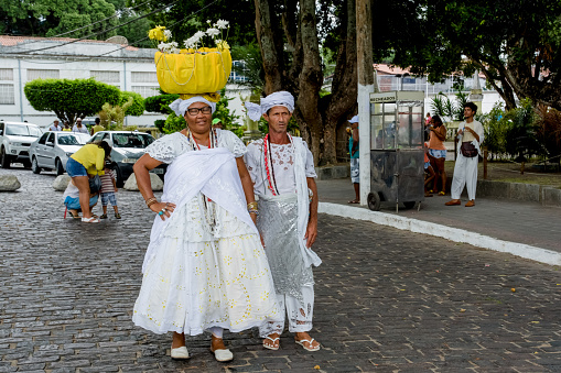Cachoeira, Bahia, Brazil - February 21, 2016: Woman of the candomble religion carrying gifts for Iemanja on her head. City of Cachoeira, Bahia.