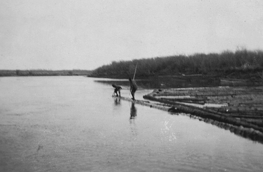 Log drivers driving logs down the Carrot River in Saskatchewan, Canada. Vintage photograph ca. 1919.
