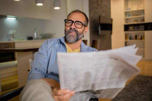 istock Man sitting and reading newspaper at home 1459788194