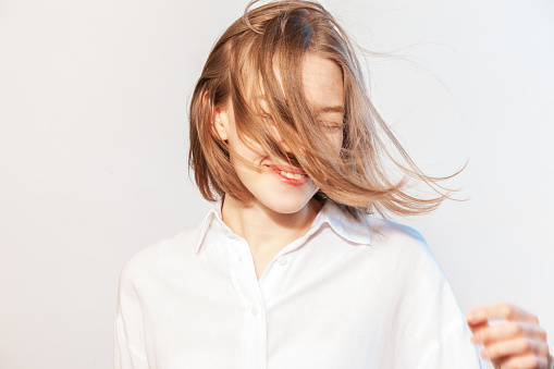 Studio portrait of happy Asian 22 year old woman in white shirt against a  white background