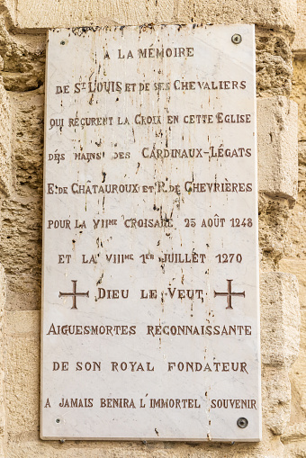 Aigues-Mortes, Gard, Occitania, France. July 4, 2022. Plaque memorializing the return of the church's cross by St. Louis and his knights, from 1270 CE.