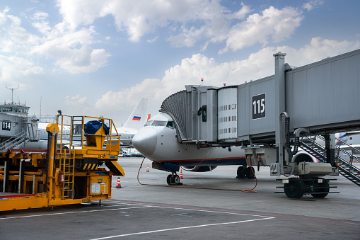 Passenger airplane on the airfield docked with passenger boarding bridge. Preparations of the airplane at the airport terminal.