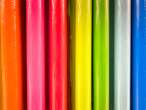 Close up of rolls of shiny rolls of color coated paper.