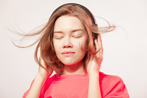 22 year old happy Asian woman listening to music with wireless headphones