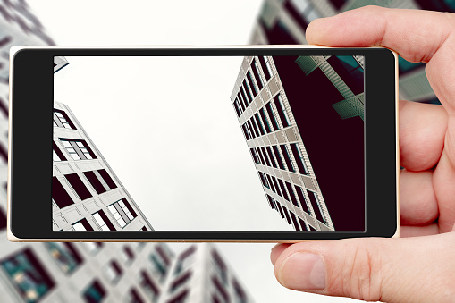Buildings of modern city on smartphone screen. View from below.