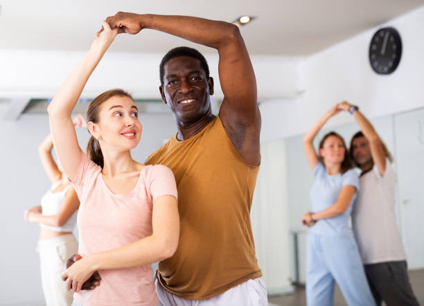 istock Positive smiling dancing couple enjoying active dancing during group training in dance hall 1459808520