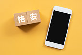 Wooden blocks with “kakuyasu” text of concept and a smartphone.