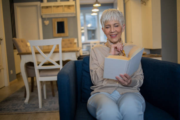 istock Happy woman reading book at home 1459817245