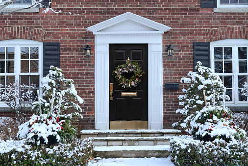Traditional older brick house in winter with Christmas decoration on front door