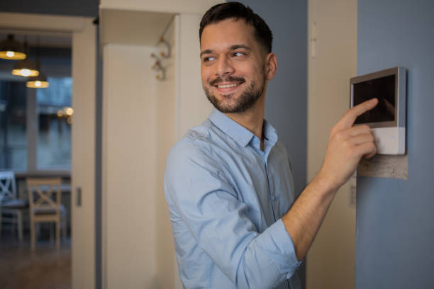istock Young man adjusts the temperature at home with a device on the wall 1459837916