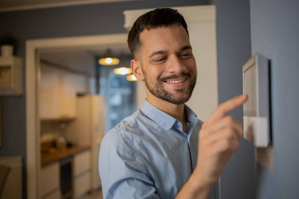 istock Young man adjusts the temperature at home with a device on the wall 1459837918
