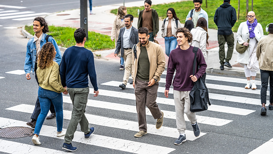 People walking across crosswalk in city downtown top view. Men and women crowd crossing highway, above wide shot