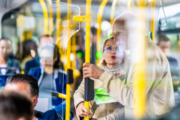 istock Elderly couple holding handrail in bus and talking 1459839636