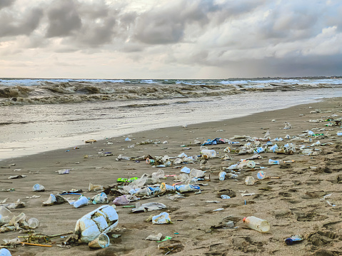 Full frame shot of dirty heap plastic waste lying on the ground covering the sand of Bali beach during rainy season