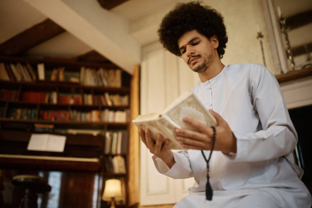 istock Middle Eastern man reading from Koran while holding misbaha beads at home. 1459845932