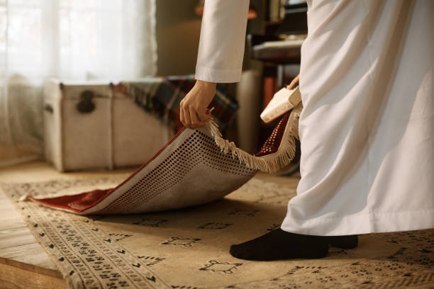 istock Close up of Arab man setting traditional carpet while preparing for prayer at home. 1459845981