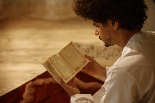 istock Young Middle Eastern man reading from Koran at home. 1459846027