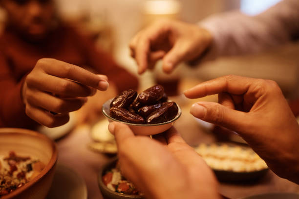 primo piano della famiglia di medio pasqua che mangia l'appuntamento del ramadan al tavolo da pranzo. - ramadan foto e immagini stock